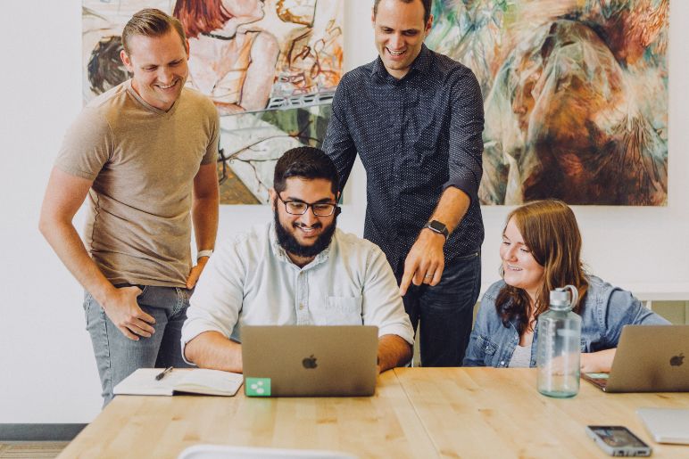 Team of 4 people looking at a laptop together