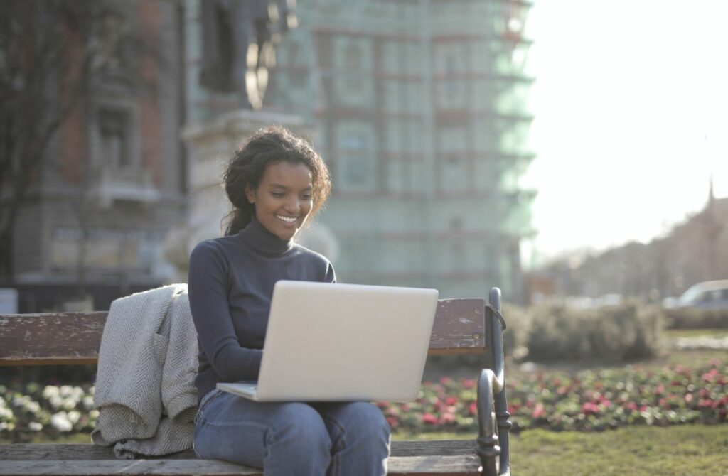 Woman working from a bench in a park.